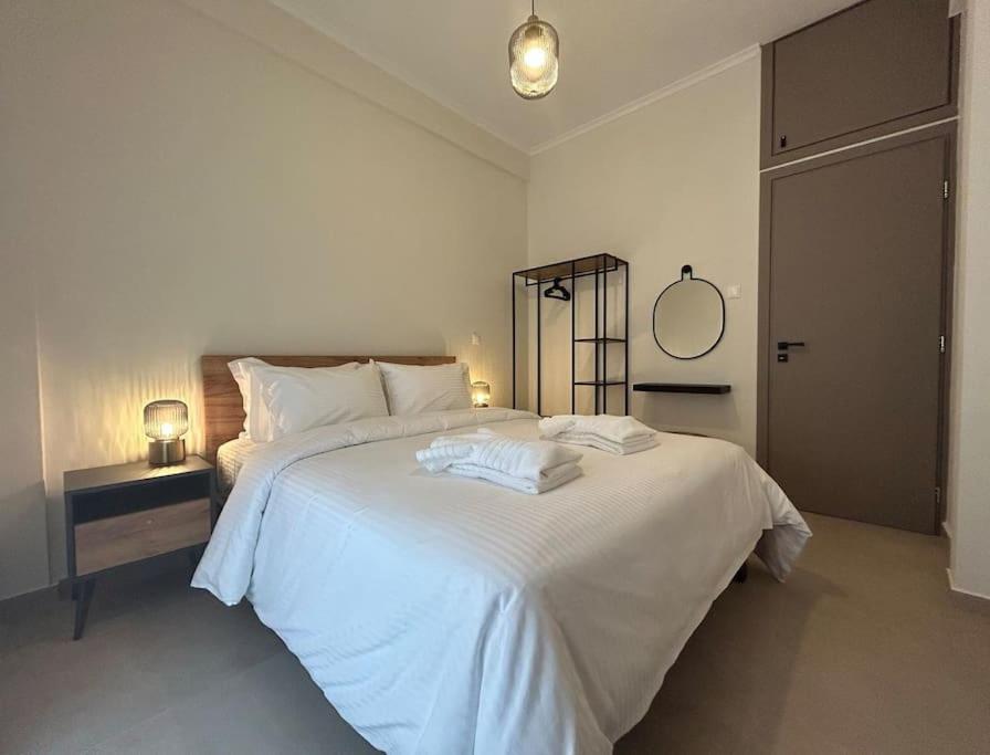 una camera bianca con un grande letto bianco e uno specchio di Urban Escape ad Atene