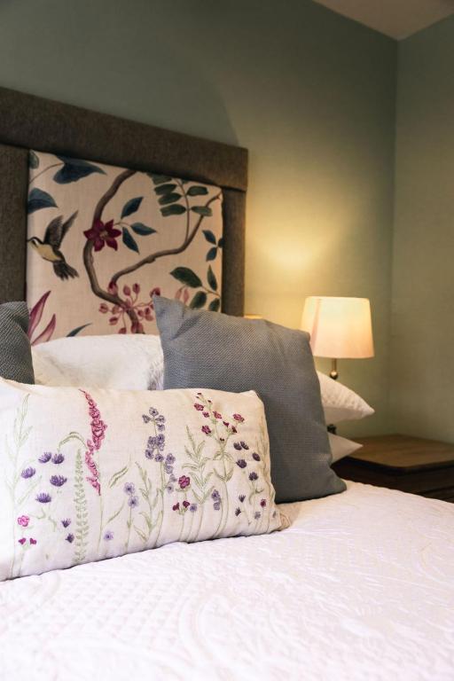 Una cama con sábanas blancas y almohadas con estampado floral. en the Cartwheel Inn, en Whitsbury