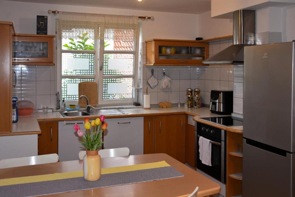 NadgoricaApartments Sina的厨房里有一张桌子，桌子上放着一瓶花