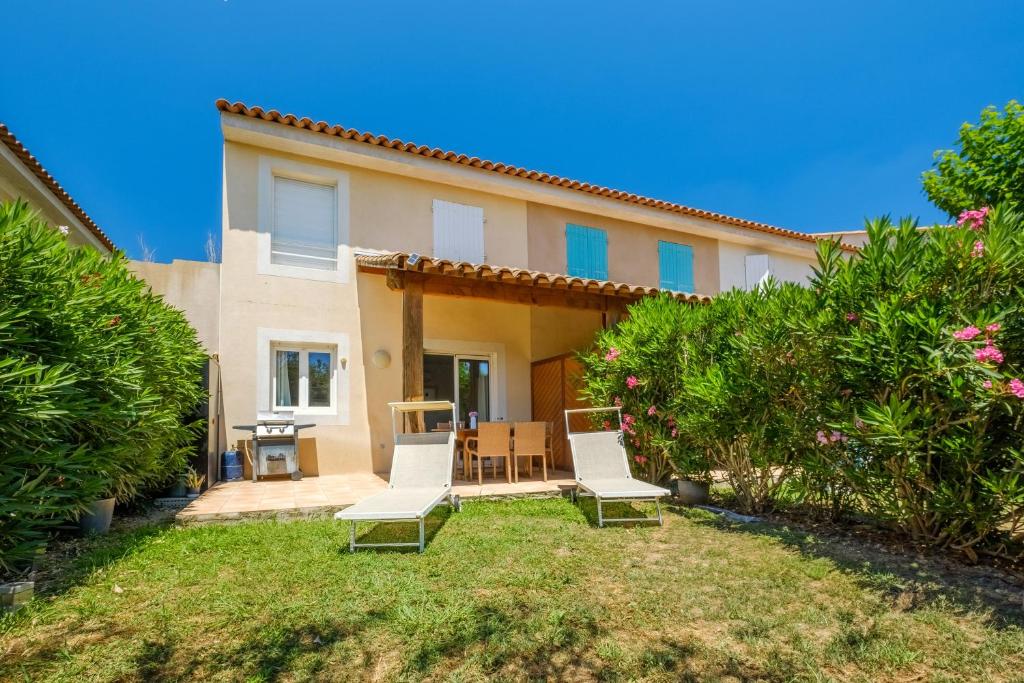 a house with two chairs and a table in the yard at La Bastide de Chaumette in Montauroux