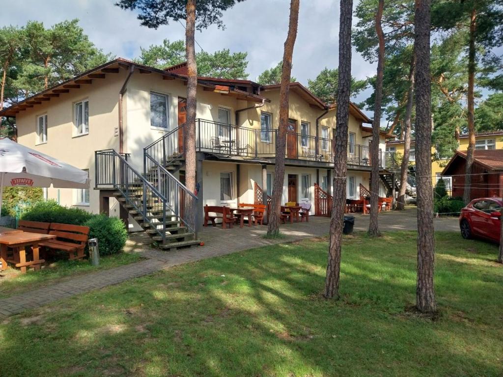 a building with a patio and tables and trees at W Sosnach E in Dziwnówek