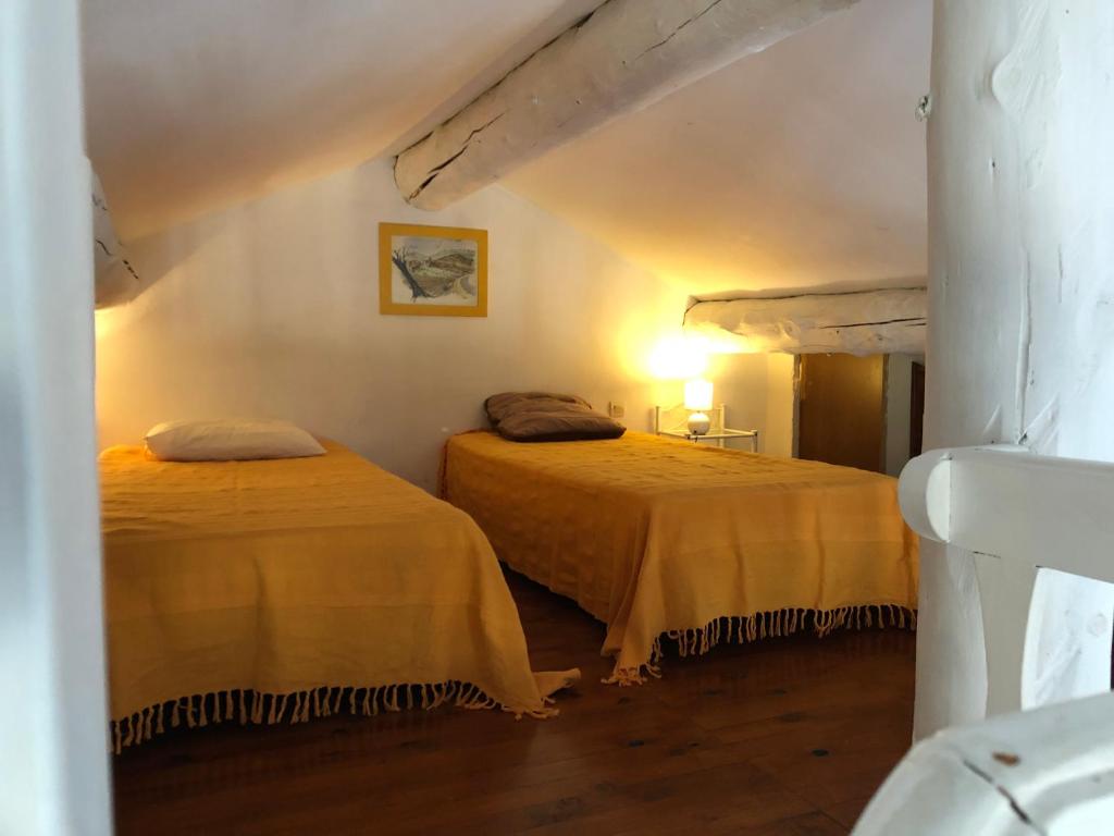 une chambre avec deux lits dans une pièce dans l'établissement Les Mazets du coulicot, à Saint-Montan