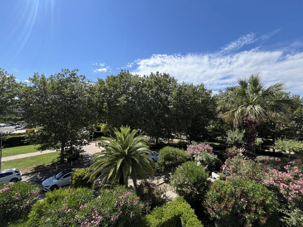 un jardin avec des arbres et des fleurs dans un parking dans l'établissement Sol-y-Days Martinic, résidence à deux pas des plages, à La Grande Motte