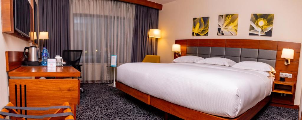 a hotel room with a large bed and a desk at Hilton Garden Inn Nairobi Airport in Nairobi
