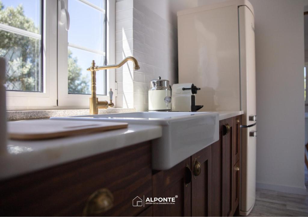 a white sink in a kitchen with a window at Quinta da Costeira - Casa Azul do Limoal by ALPONTE in Arcos de Valdevez