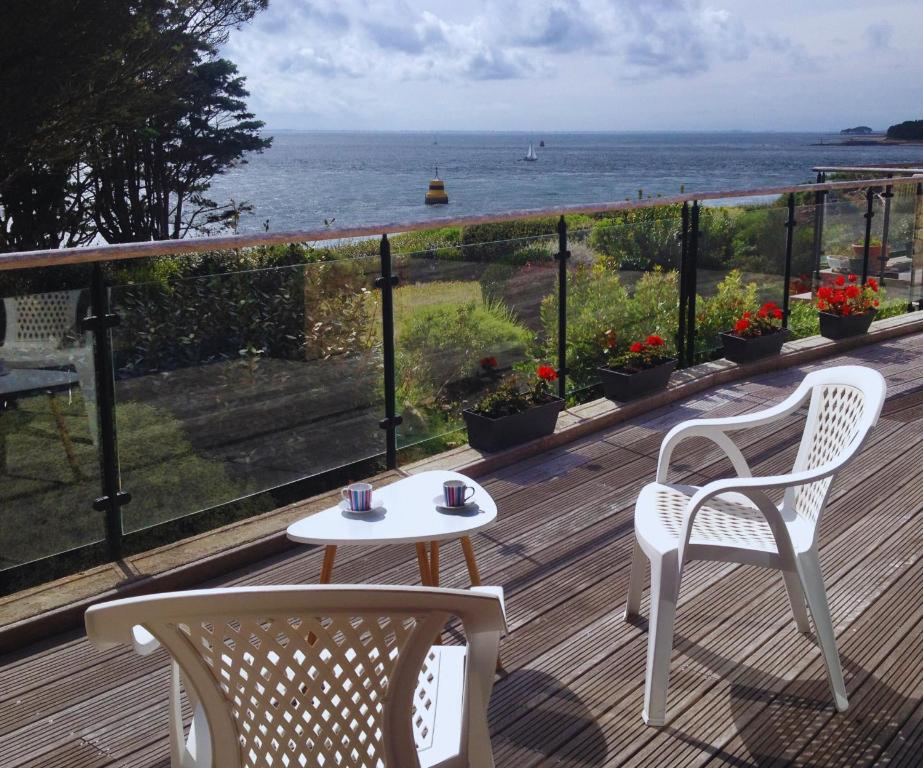 two chairs and a table on a deck with the ocean at Vacances au plus proche de la Petite Mer in Arzon
