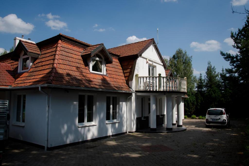 a white house with a roof with a balcony at RestHouse - wakacyjny dom nad jeziorem in Wądzyn