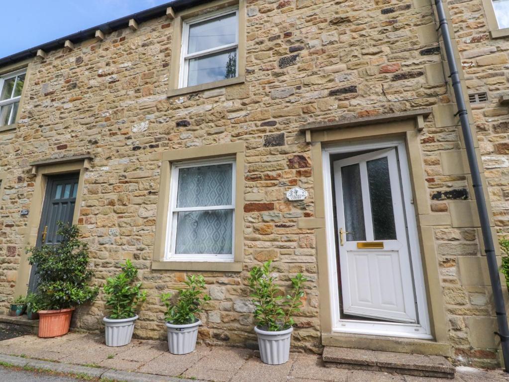 a brick house with potted plants in front of it at Ted's Cottage in Skipton