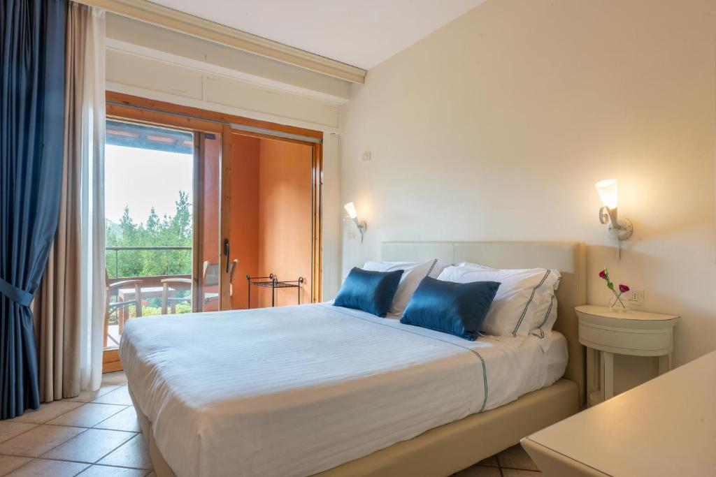 a bedroom with a large bed with blue pillows at Boutique Hotel Torre Di Cala Piccola in Porto Santo Stefano