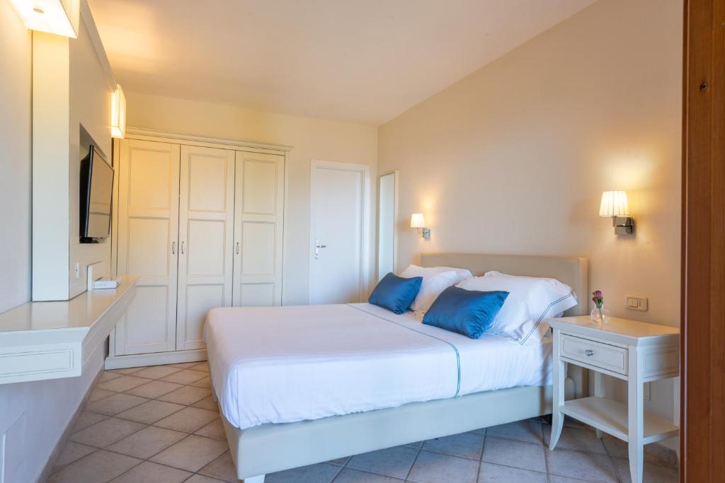 a bedroom with a bed with blue pillows at Boutique Hotel Torre Di Cala Piccola in Porto Santo Stefano