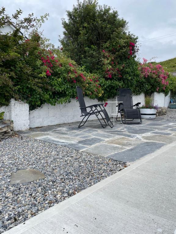 two chairs sitting on a stone patio with flowers at Marta Studio Apartment in Ennistymon