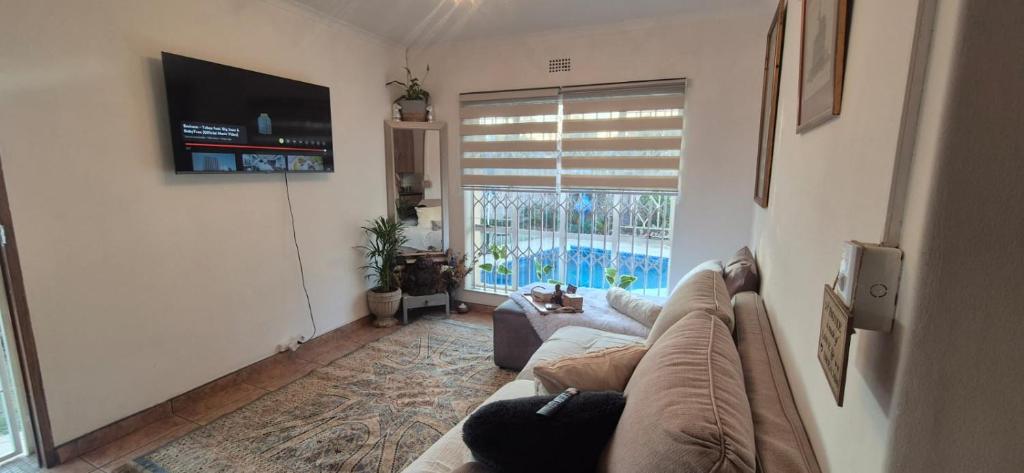 a living room with a couch and a large window at Saint Blaize Cottage in Boksburg