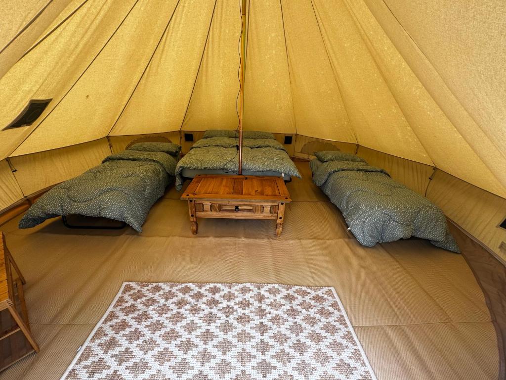 a group of beds in a tent with a table at Polladras Holiday Park in Helston