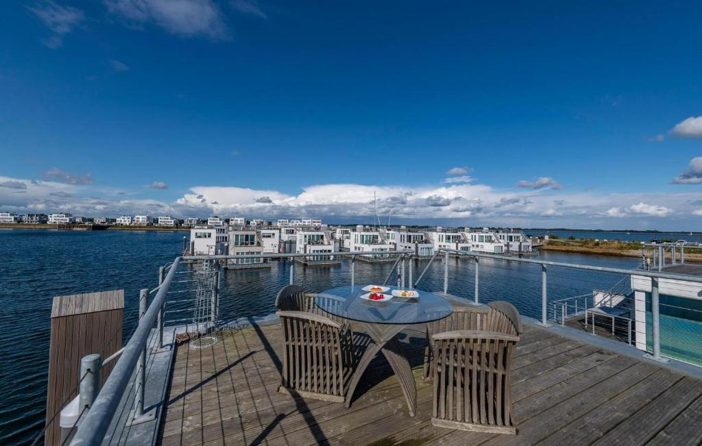 a deck with a table and chairs on the water at Waterfront in Olpenitz