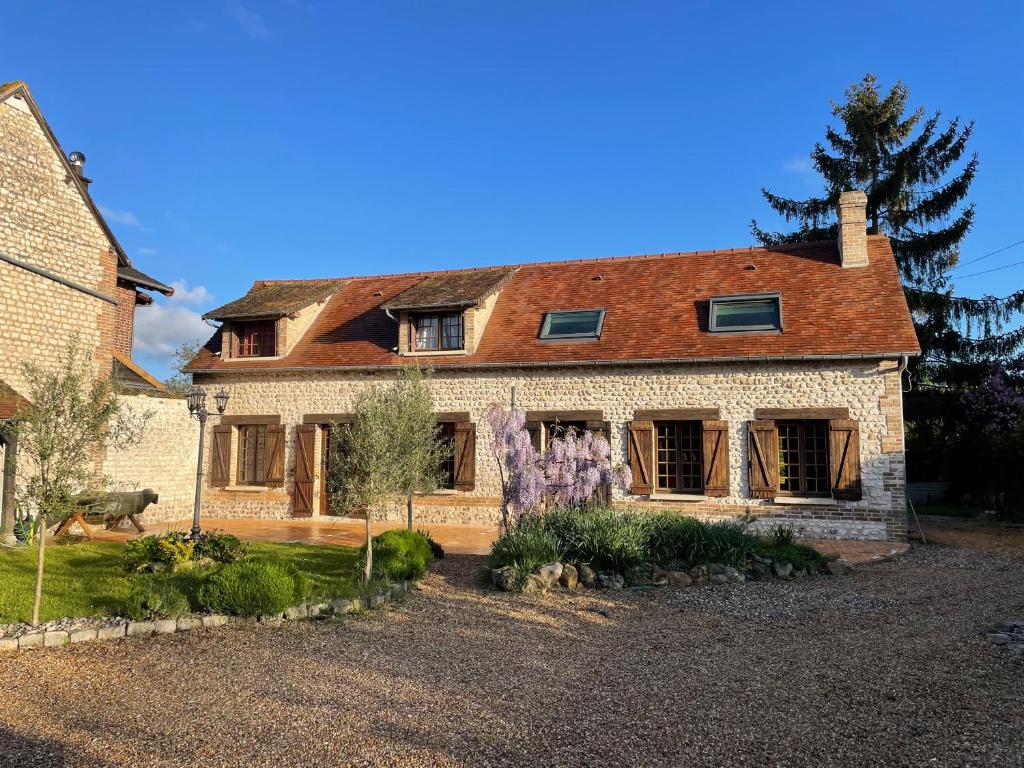 une grande maison en briques avec un jardin en face de celle-ci dans l'établissement Grande Maison en bord de Seine, à Muids