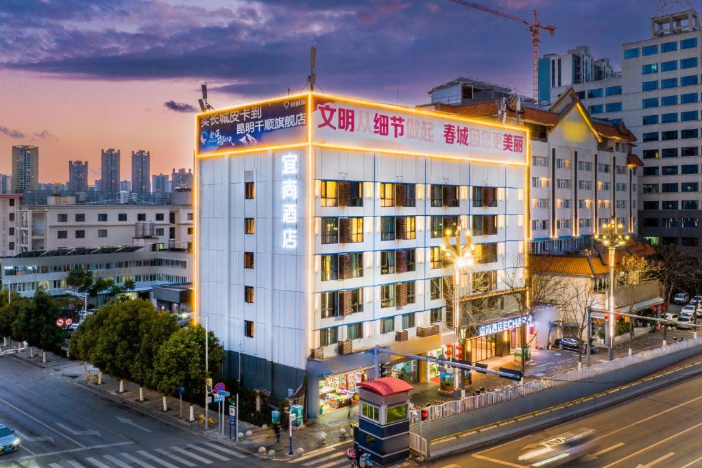 a large white building on a city street at night at Echarm Hotel - Kunming Station South Asia Style Street Branch in Kunming