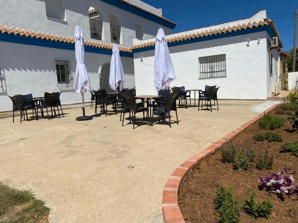 a patio with a table and chairs and umbrellas at Alojamiento Rural Al´Mare in Conil de la Frontera