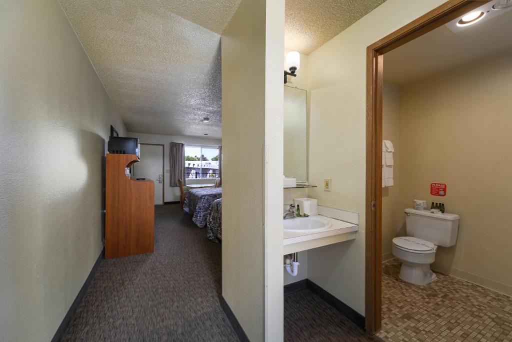 a bathroom with a sink and a toilet and a bed at Cocusa Motel in Burlington