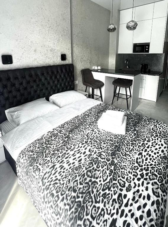 a bedroom with a black and white bed with two chairs at VEM Apartment Калипсо in Odesa