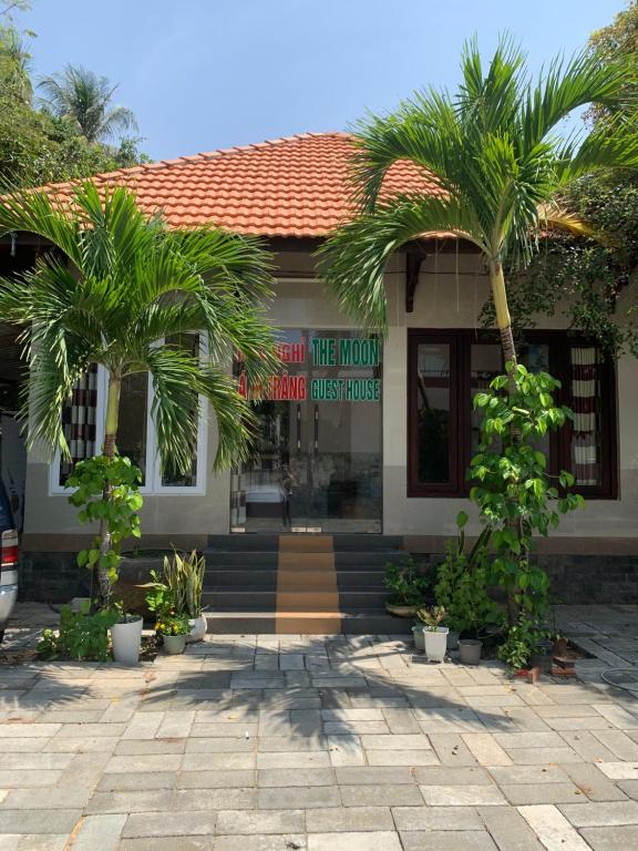 a building with two palm trees in front of it at Ánh Trăng Homestay in Ấp Thiện Phước
