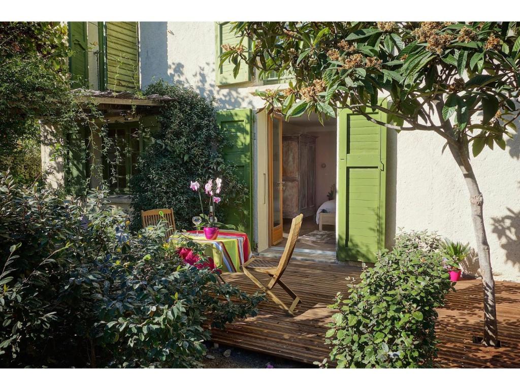 um alpendre com uma porta verde, uma mesa e cadeiras em Les Jasmins em Collioure