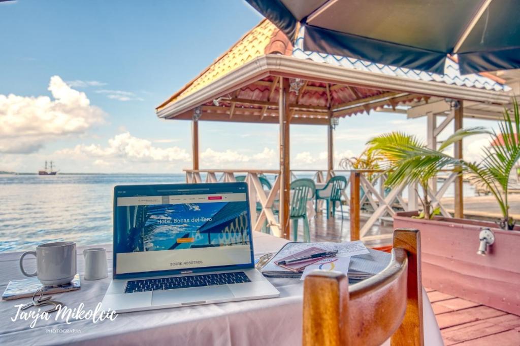 a laptop computer sitting on a table next to the ocean at Hotel Bocas del Toro in Bocas del Toro