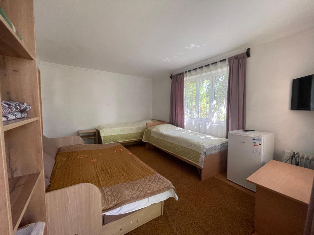 a small room with two beds and a window at Family Guest House in Cholpon-Ata