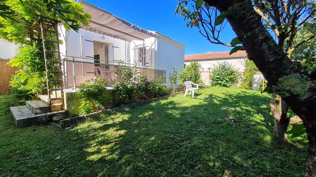 une cour d'une maison avec une chaise dans l'herbe dans l'établissement Saint Georges de Didonne - QUARTIER IDEAL POUR SE RESSOURCER - MAISON rénovée, à Saint-Georges-de-Didonne