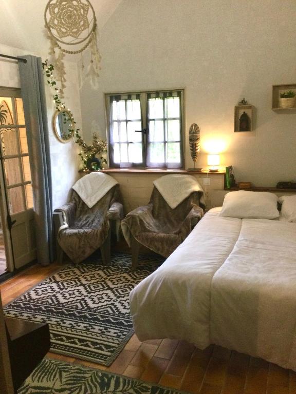 une chambre avec un lit et deux chaises et une fenêtre dans l'établissement Bungalow 2 pièces, SDB, terrasse, Piscine de mai à octobre, à Gauville