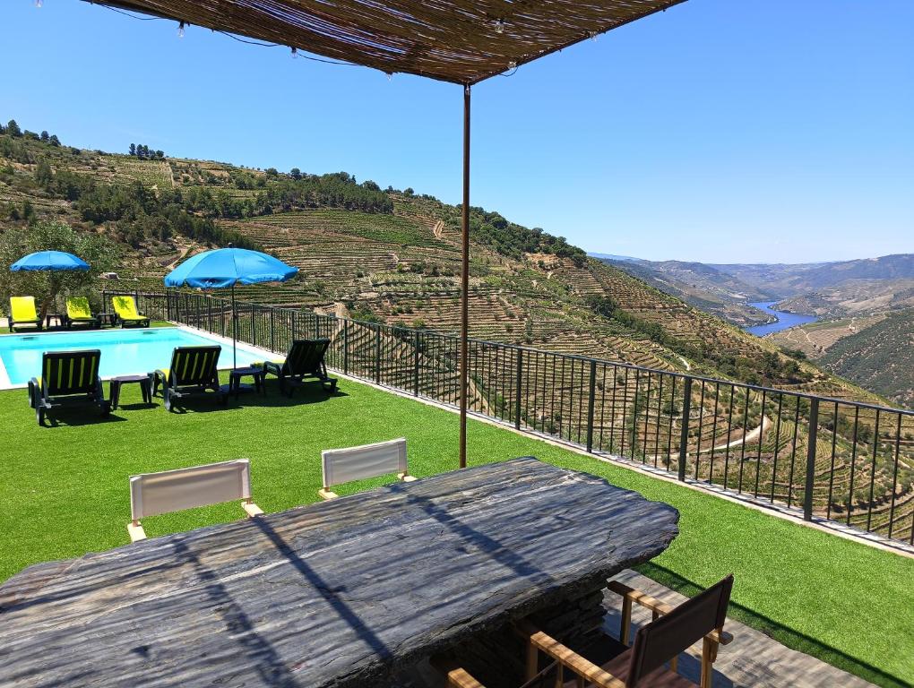 a wooden table with chairs and a view of a hill at Quinta do Fraguil - Douro Valley in Valença do Douro