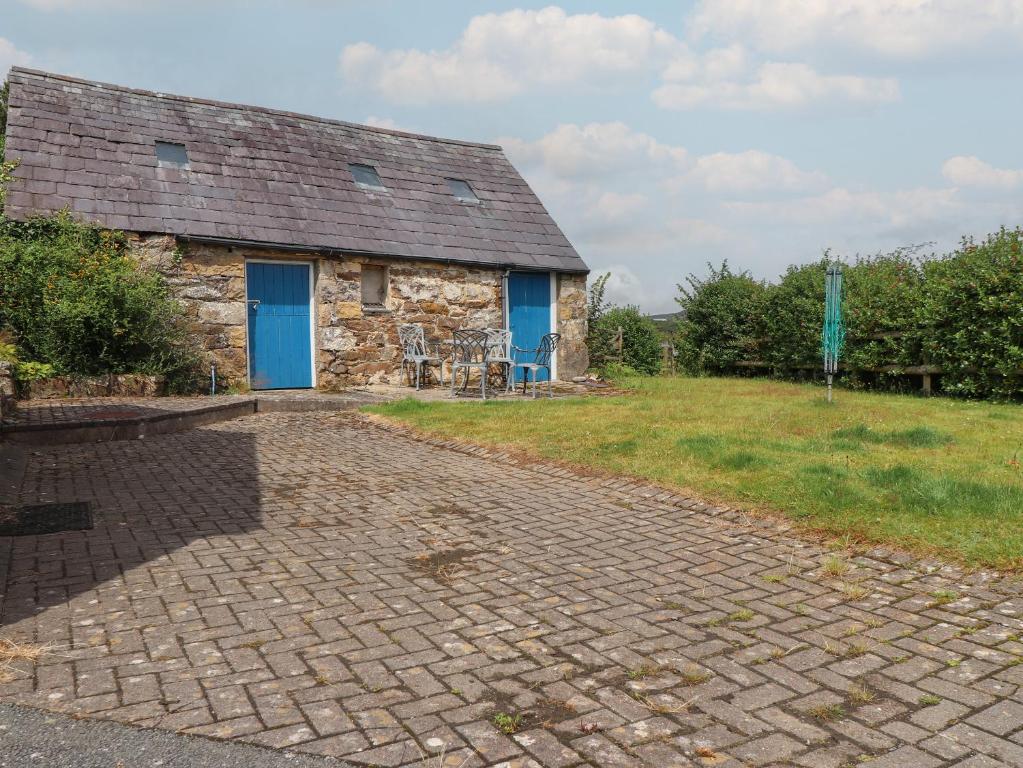 a stone building with a blue door and a brick driveway at The Grain Store in Abersoch