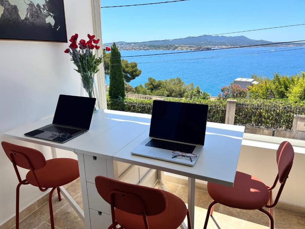 - deux ordinateurs portables sur une table blanche avec vue sur l'océan dans l'établissement Breathtaking Mediterranean Views from Renovated Cosy Nest, Walk to Portissol Beach and Port, à Sanary-sur-Mer