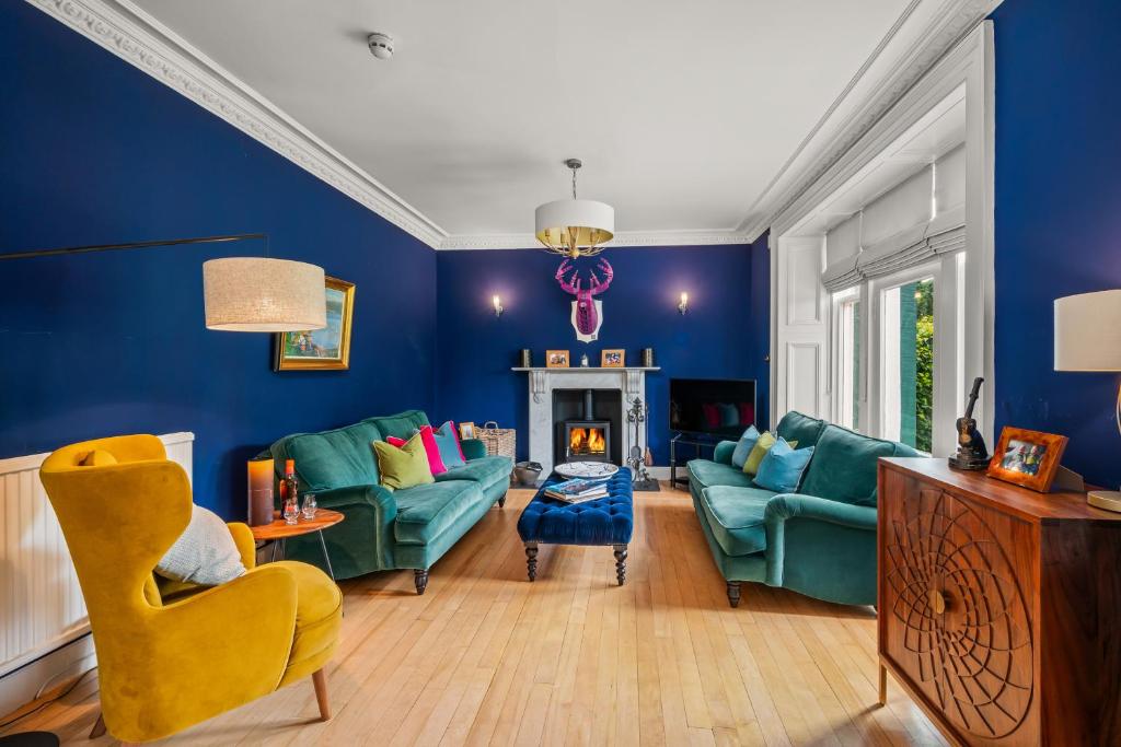 a living room with blue walls and green furniture at Rosebank House - 12 Guests, 6 Ensuite Bedrooms, EV point, Games Rooms, Wood Burner, Pet Friendly! in Blairgowrie