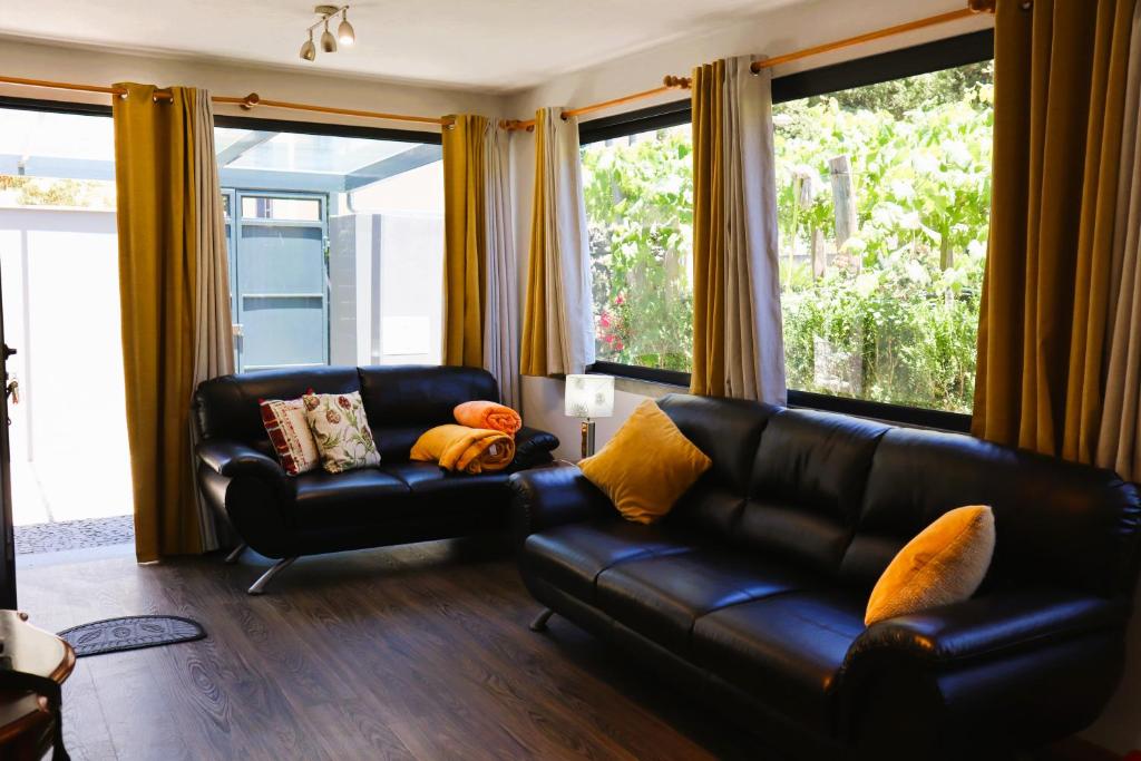 a living room with a black leather couch and windows at Marialina, By OP in São Vicente