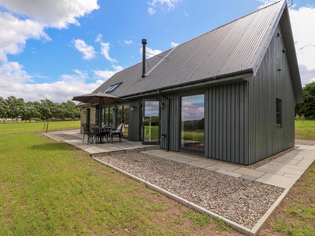 a large metal building with a roof and a patio at Strawberry Cottage in Blairgowrie