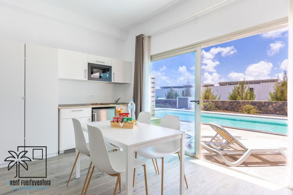 Una cocina y un comedor con una mesa y sillas blancas. en Lola Loft 1 Lajares iRent Fuerteventura, en La Oliva