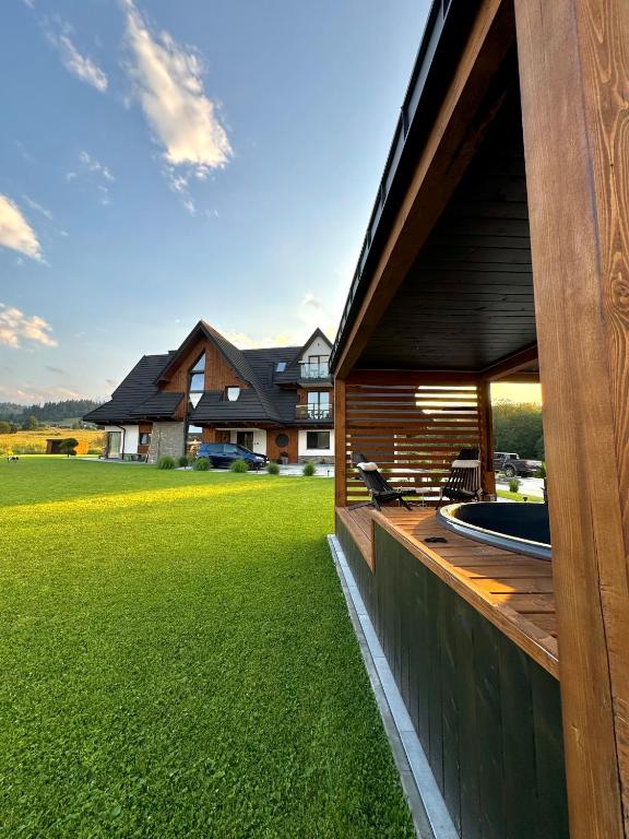 a house with a deck with a grass yard at Hill House Apartamenty w cichej i spokojnej okolicy blisko Term Bania gorąca balia,bilard in Białka Tatrzańska