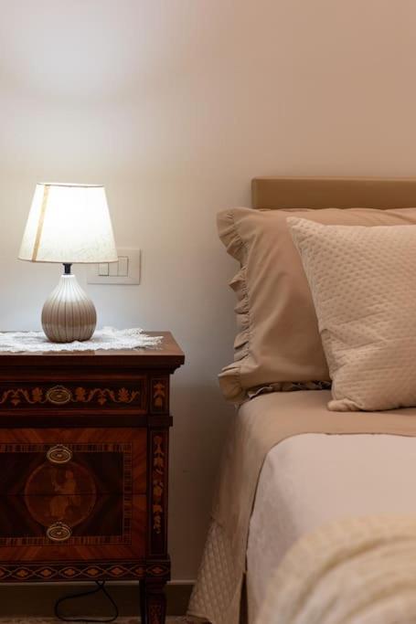 a bed with a table with a lamp on it at Casa EleMar in Barletta