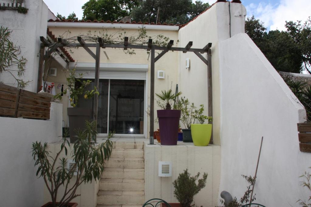 une maison blanche avec des escaliers et des plantes devant elle dans l'établissement PETITE MAISON D'HÔTE et SON PATIO au PIED DE NOTRE-DAME, à Marseille