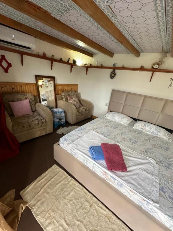 a bedroom with a large bed and two chairs at Villa Zeko in Gjirokastër
