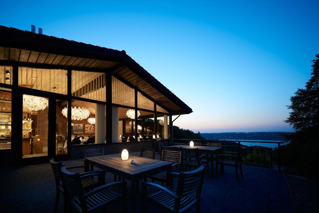 eine Terrasse mit Tischen und Stühlen und ein Gebäude in der Unterkunft Munkebjerg Hotel in Vejle