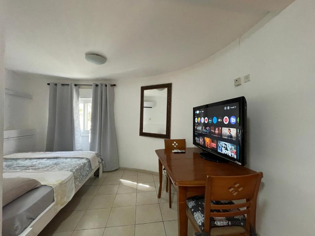 a bedroom with a bed and a desk with a flat screen tv at Eilat Beach House in Eilat