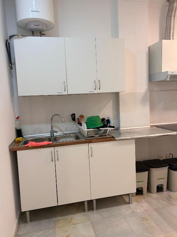 a kitchen with white cabinets and a sink at Hostel Sorolla Playa in Málaga