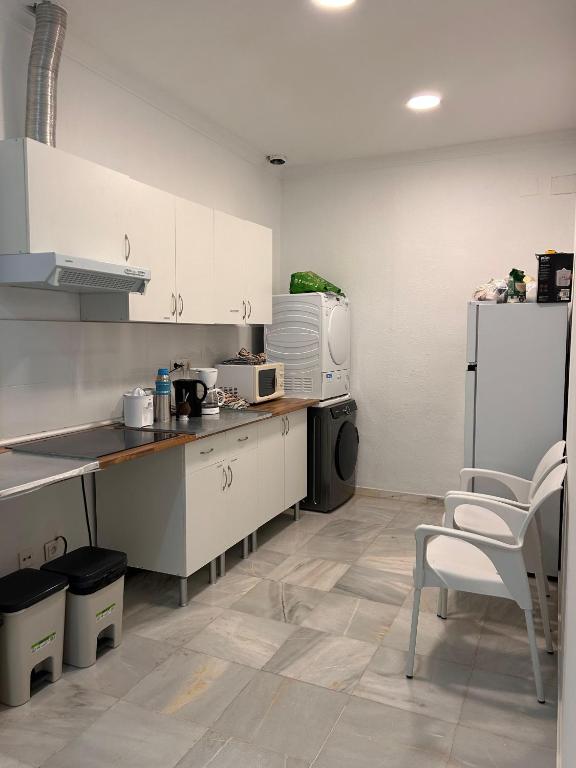 a kitchen with white cabinets and a table and chairs at Hostel Sorolla Playa in Málaga