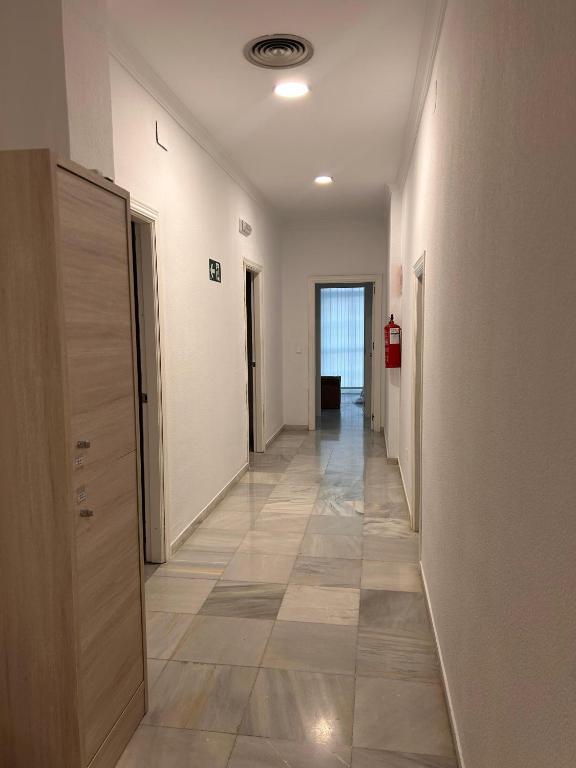 a hallway with white walls and a tile floor at Hostel Sorolla Playa in Málaga