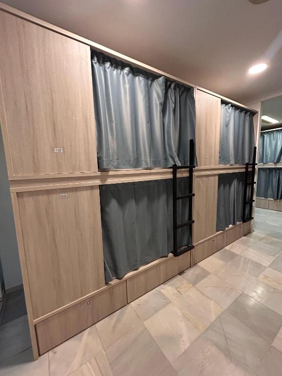 a row of wooden closets with black curtains at Hostel Sorolla Playa in Málaga