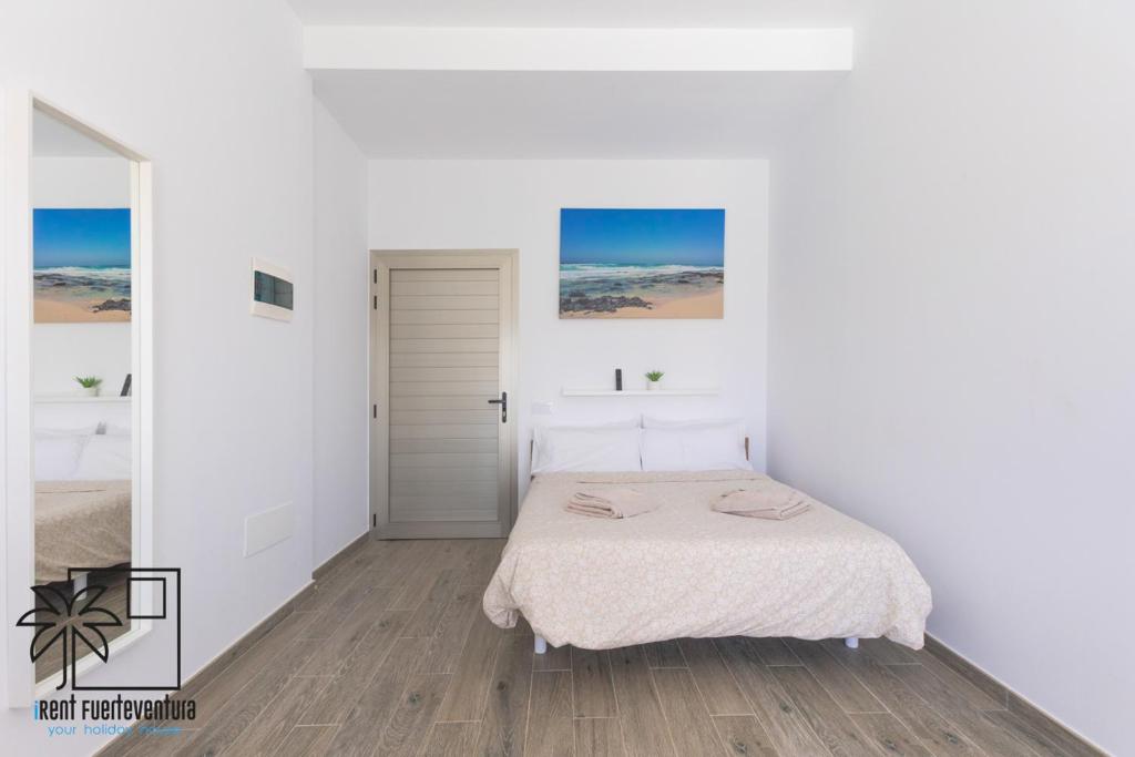 Un dormitorio blanco con una cama y una puerta. en Lola Loft 4 Lajares iRent Fuerteventura, en La Oliva