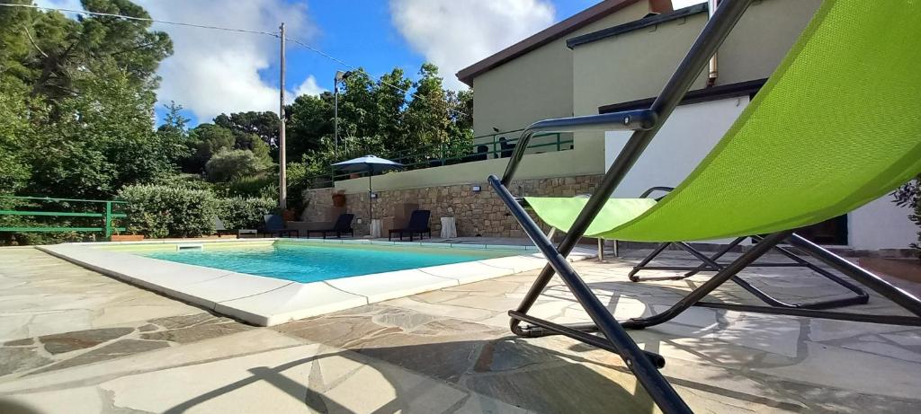 ein grüner Stuhl neben einem Swimmingpool in der Unterkunft Villa D'Anna in Cefalú