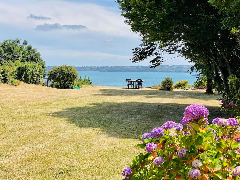 プルバスラネックにあるHavre de paix avec vue imprenable sur la merの水辺に2つのピクニックテーブルと花が咲いている公園