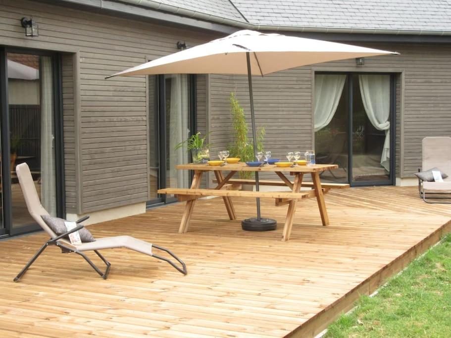 une terrasse en bois avec une table et un parasol dans l'établissement Gîte de la chouette, à Hattenville